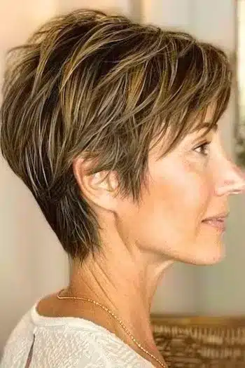 Choppy pixie wedge with highlights, side view of a woman with brown hair and blonde pieces