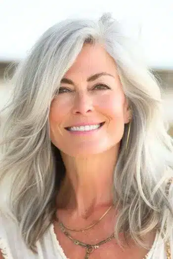 Medium-length layers with side swept bangs on a smiling woman with silver gray hair