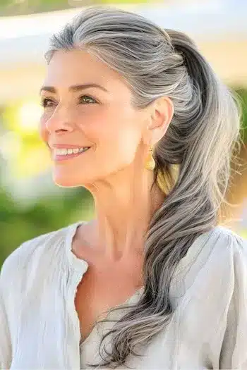 Salt and pepper wavy ponytail on a smiling woman in her 60s with gray hair