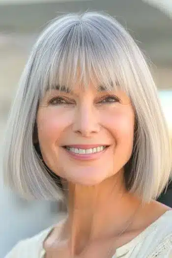 Blunt bob with straight bangs on a smiling older woman with gray hair