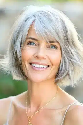 Voluminous bob with bangs on a woman in her 40s with silver hair