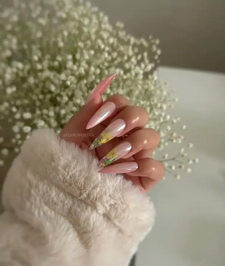 Stiletto-shaped nails with milky white base, pale pink tips, chrome powder, and dried florals